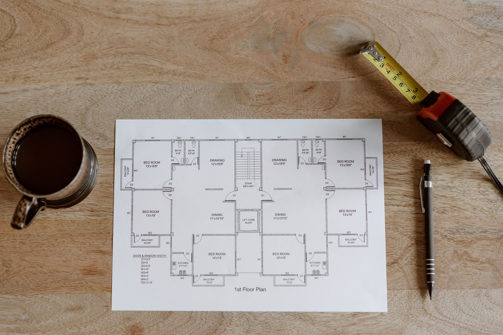 Top view of set of plan of room with tape measure and pen for work for architect with cup with coffee on wooden table in soft daylight